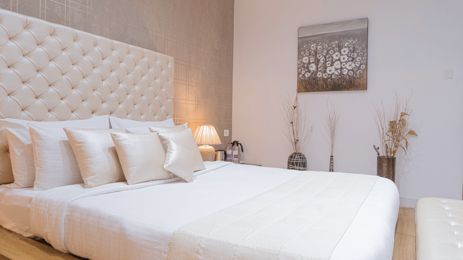 Side view of the bedroom of the Suite at Sarovar Portico, Bhubaneswar, showcasing its plush king size bed with an upholstered headboard placed in a room with minimal Bohemian interiors.