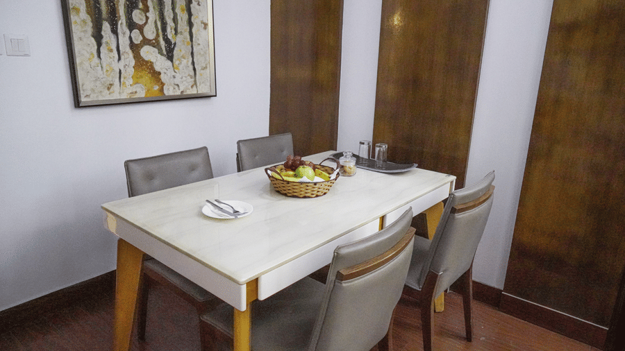 Dining area featuring a table with 4 chairs, and a fruit basket placed on it in the Suite of Sarovar Portico, Bhubaneswar.