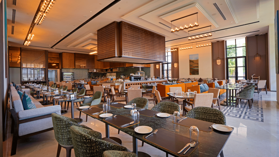 View of CHITHIRAI restaurant at The Residency Signature Madurai with lounge seating, green chairs, wooden panelling, and warm ambient lighting.