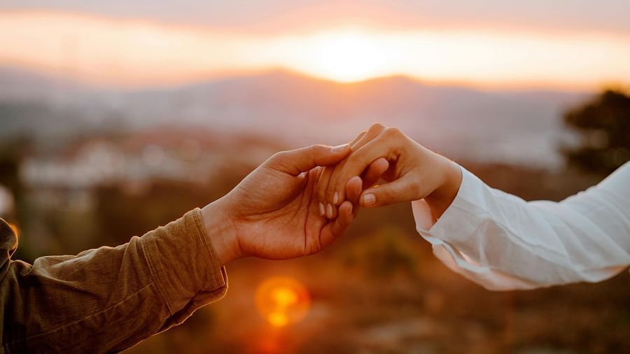 A couple holding hands in a romantic sunset backdrop