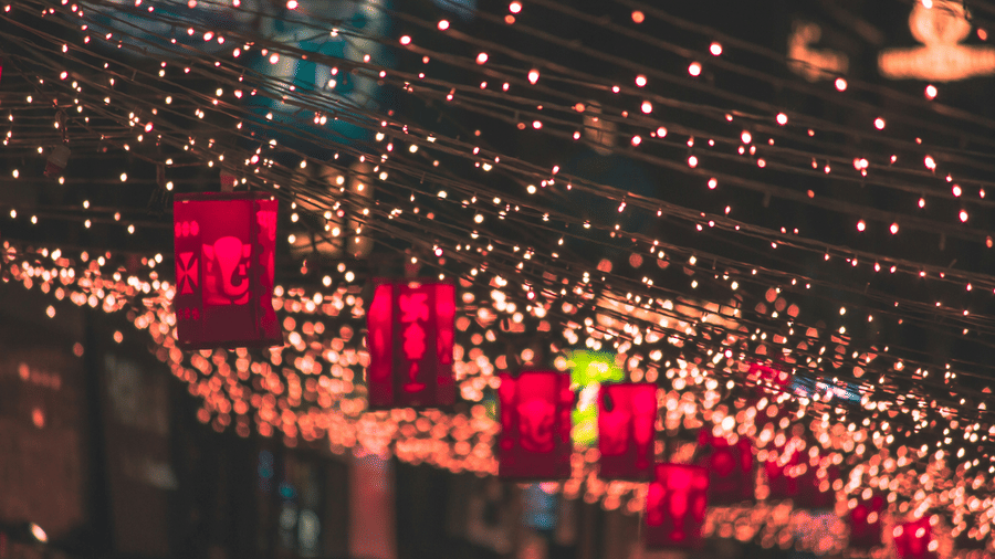 An image of beautiful decoration above a street with fairy lights and red coloured paper lanterns.