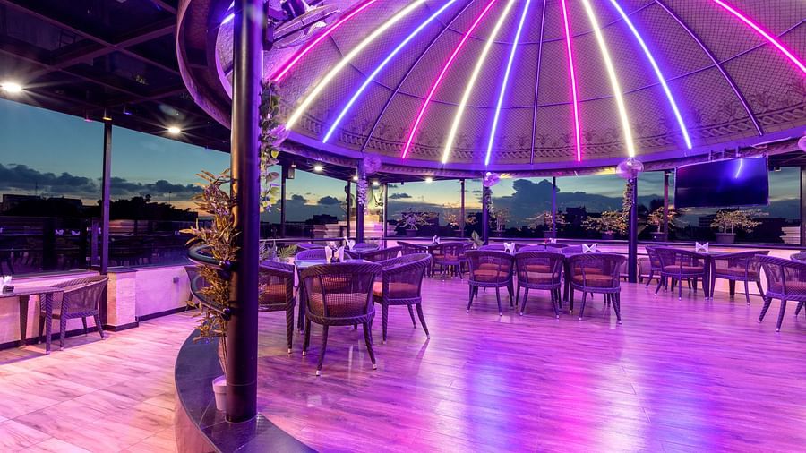 Sudaka dome with multiple tables and chairs and vibrant lights - The Saibaba Hotel