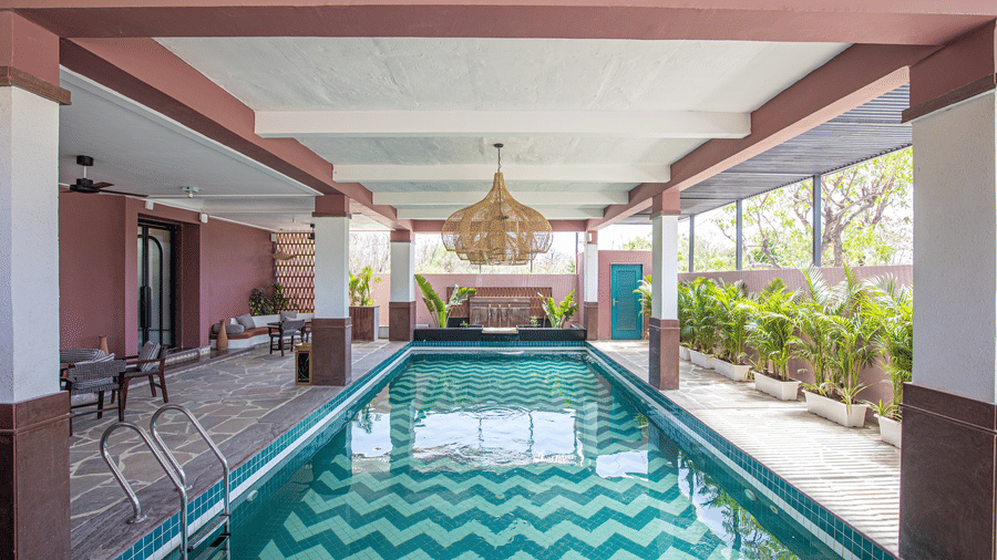 Indoor swimming pool at The Sierra Udaipur surrounded by plants on one side and seating area on the other side.. 