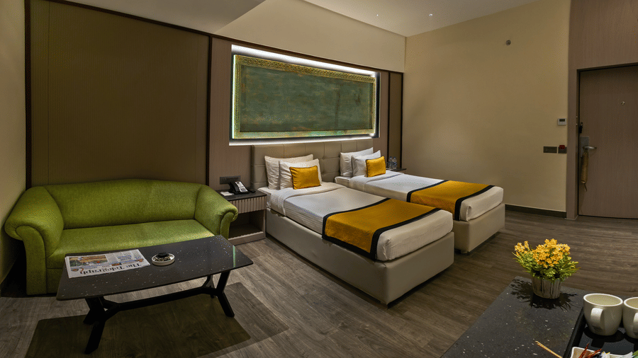 Contemporary hotel room with twin beds, seating area and warm interiors at The Sonnet, Jamshedpur.
