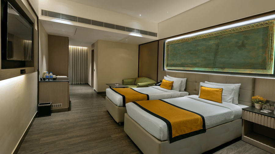 Bright guest room with twin beds, work desk and large window at The Sonnet, Jamshedpur.