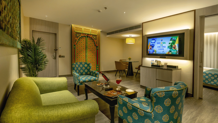 Spacious suite living area with green seating, modern decor and TV at The Sonnet, Jamshedpur.
