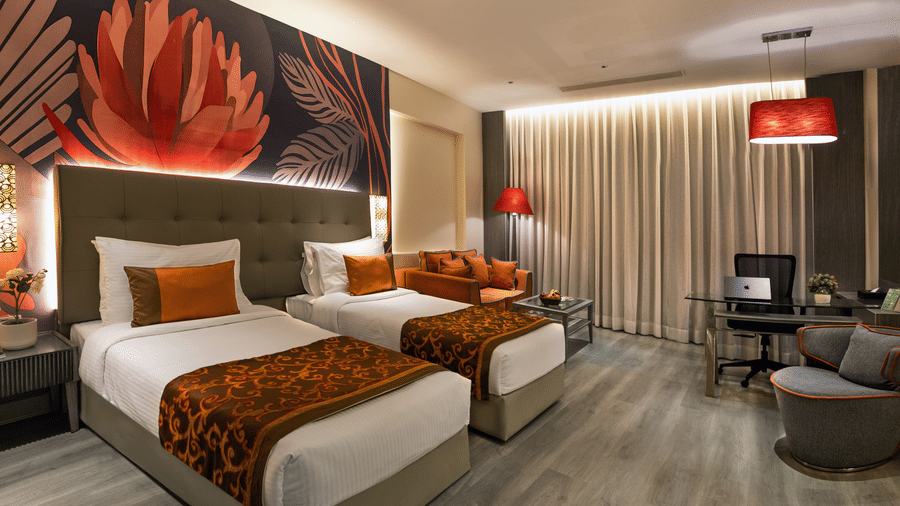 Executive Room at The Sonnet, Kolkata with twin beds, bedside tables, a television and seating area.