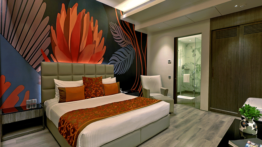 Suite bedroom at The Sonnet, Kolkata featuring a double bed, patterned feature wall, bedside tables and a television.