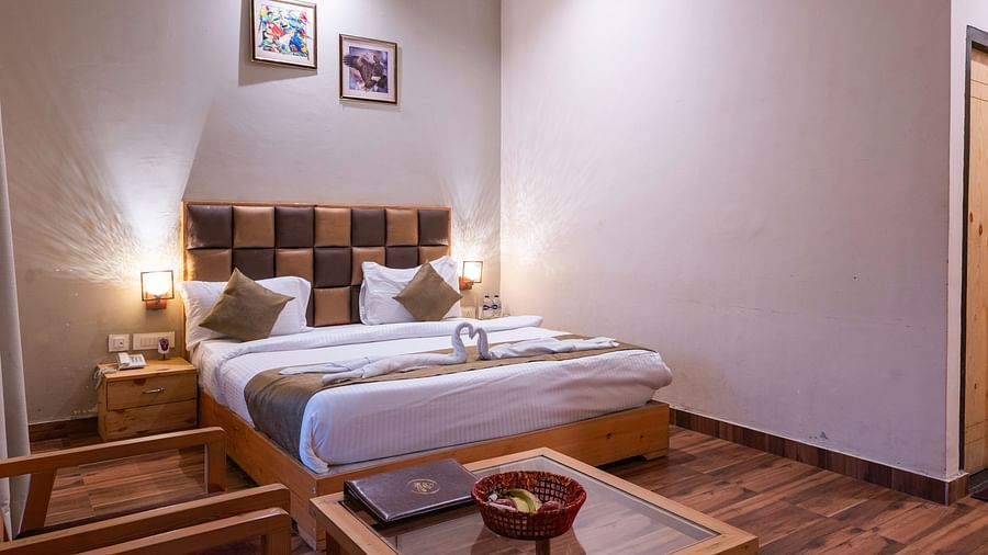 Cosy twin-bed room with wooden floor and wall decor at The Tattwaa Corbett Spa & Resort.