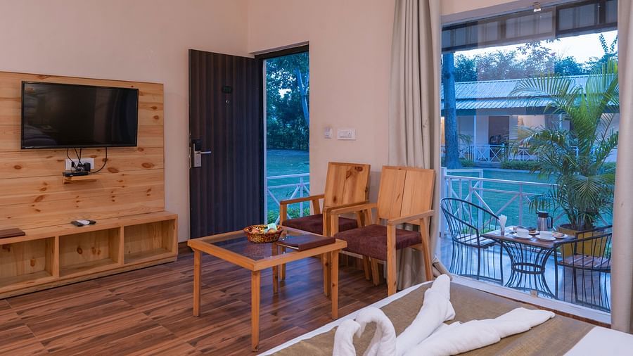 Cabana-style room with warm ambience, bed and chairs at The Tattwaa Corbett Spa & Resort.