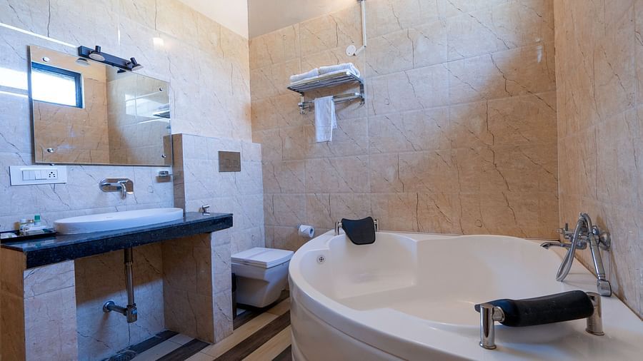 Bathroom with vanity, mirror and jacuzzi at The Tattwaa Corbett Spa & Resort.