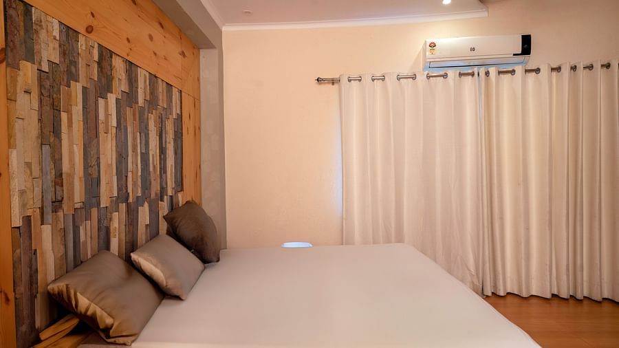 Minimalist bedroom design with a king bed and curtained windows at The Tattwaa Corbett Spa & Resort.