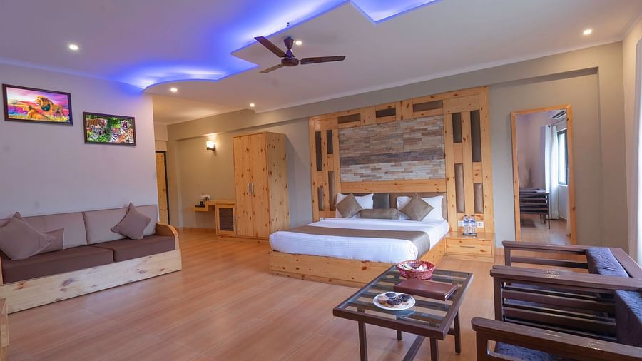 A bedroom with a king bed and sitting area , wall decor and blue lights at The Tattwaa Corbett Spa & Resort.