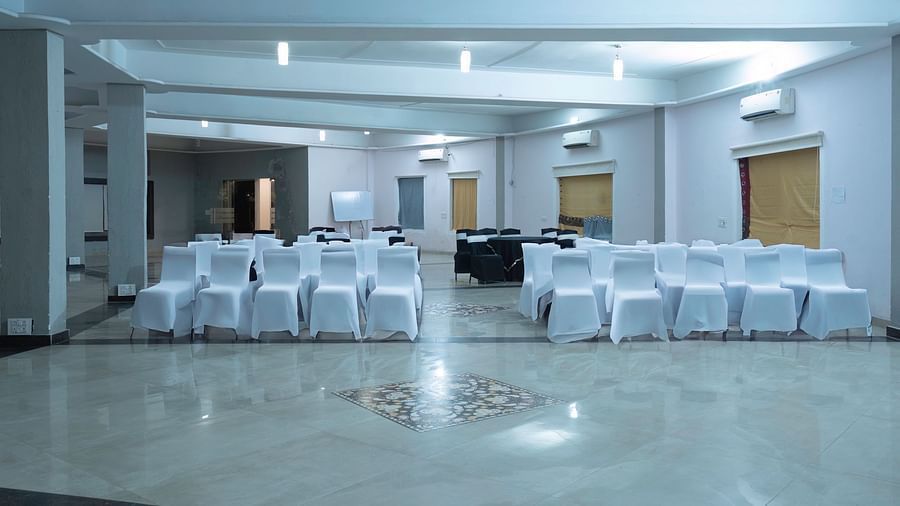 Elegant banquet hall at The Tattwaa Corbett Spa & Resort with white chairs.