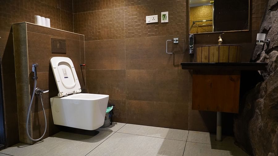 A modern bathroom with a white toilet and sink, set against dark tiled walls. | Premium Forest view 2 Bedroom Interconnecting Suite Cottage with Balcony | The Wild Trails Munnar