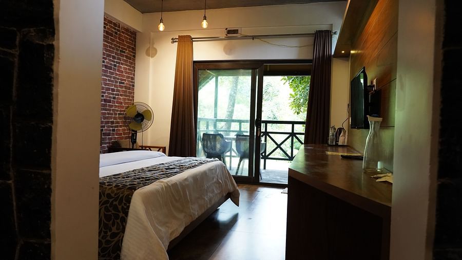 A spacious bedroom with a comfortable bed and direct access to an outdoor balcony. | Premium Forest View Cottage With Balcony | The Wild Trails Munnar