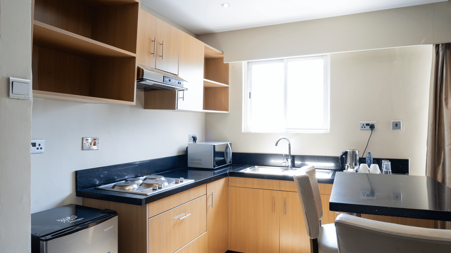 The kitchen area of the Club Room at The Zehneria, Nairobi, featuring a stove top, wooden cabinets, and a sink.