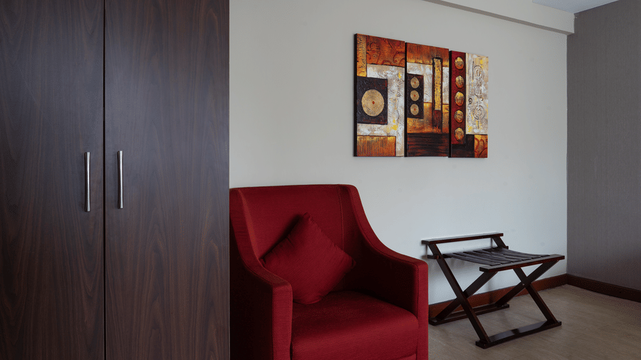 A close up of a red couch placed beside a wardrobe inside the Club Room at The Zehneria, Nairobi.