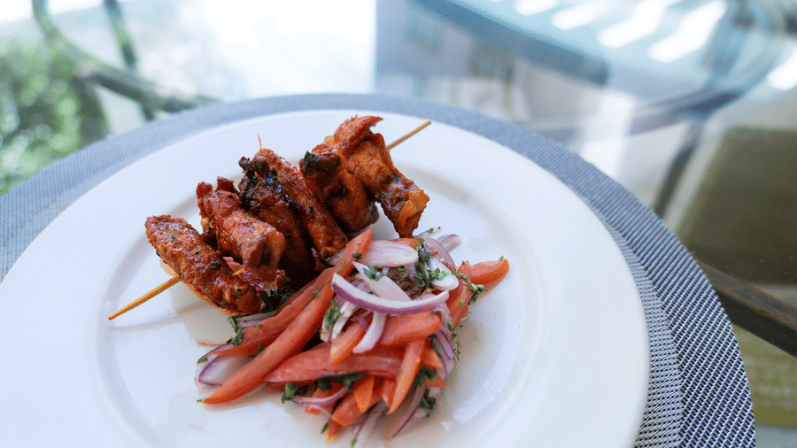 Grilled chicken skewers served with fresh vegetables on a white plate at The Zehneria, Nairobi