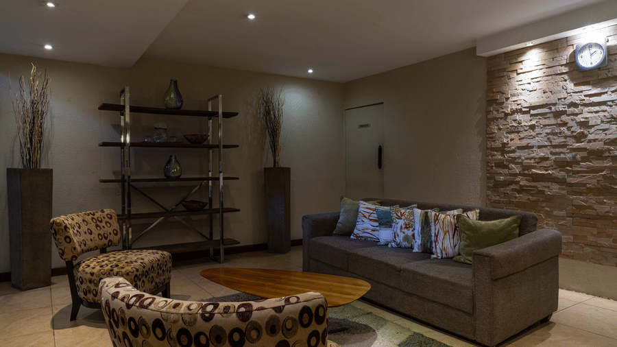 The lobby area at The Zehneria, Nairobi, featuring warm lighting, two large couches, a comfy chair, and a teapoy.