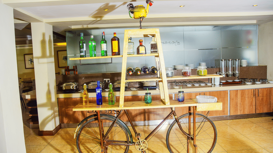 A bar counter with decorative cycle cart display at the NBO BAR | The Zehneria, Nairobi