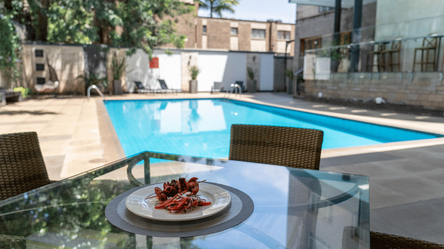 Poolside dining setup with plated appetiser near the swimming pool at The Zehneria, Nairobi
