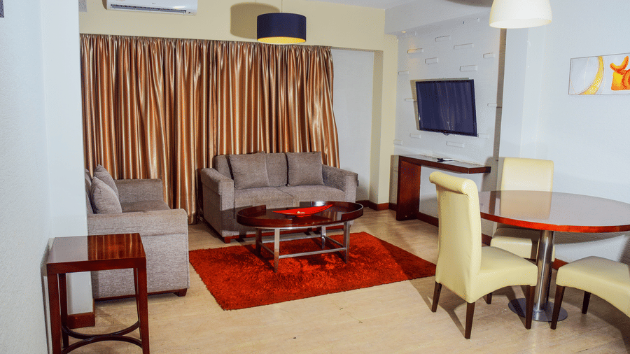 Spacious living area of a suite at The Zehneria, Nairobi featuring sofa seating, air-conditioning, a TV, and a dining table.