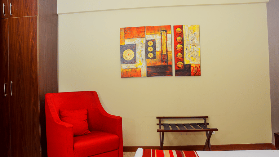 Comfortable guest room corner with red armchair seating inside the Superior Room at The Zehneria, Nairobi