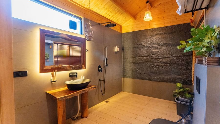 Modern bathroom with rustic wooden ceiling, stylish basin, sleek black fittings, warm lighting at Themis Farm House.
