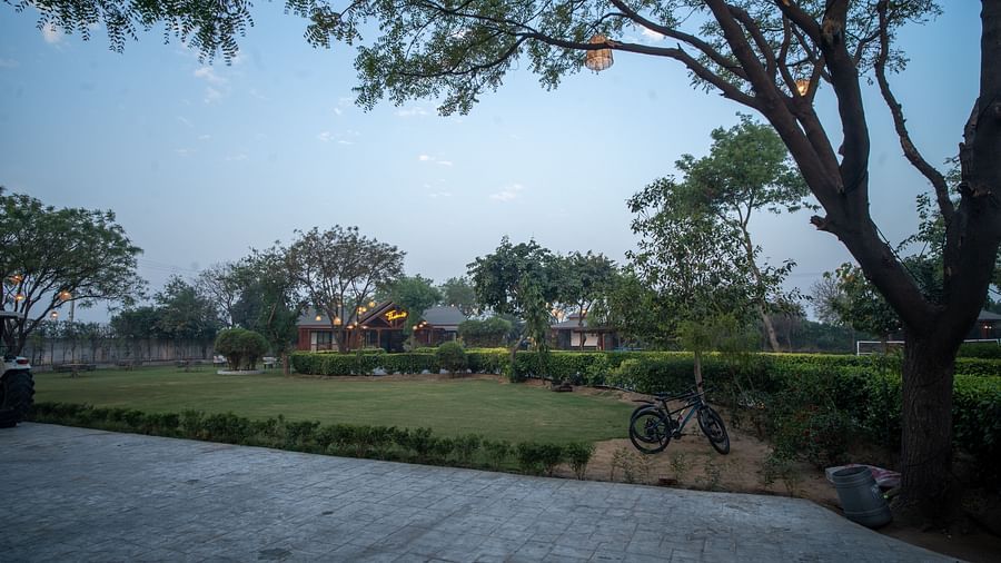 Themis Farm House features a green lawn, trees, and distant buildings under a dusky sky.