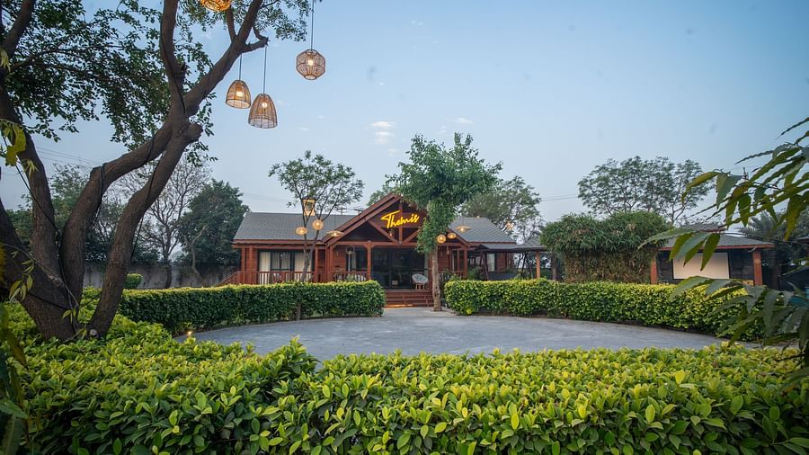 Themis Farm House villa surrounded by greenery, with hanging lanterns and a clear blue sky overhead.