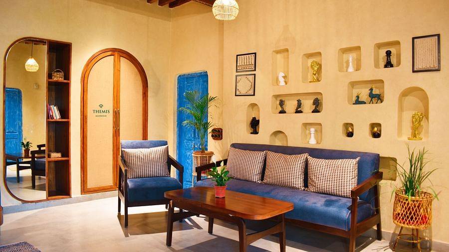 a red flower vase placed by a blue couch in Classic Villas at Themis Mudhouse - A Nature's Retreat Resort & Wellness