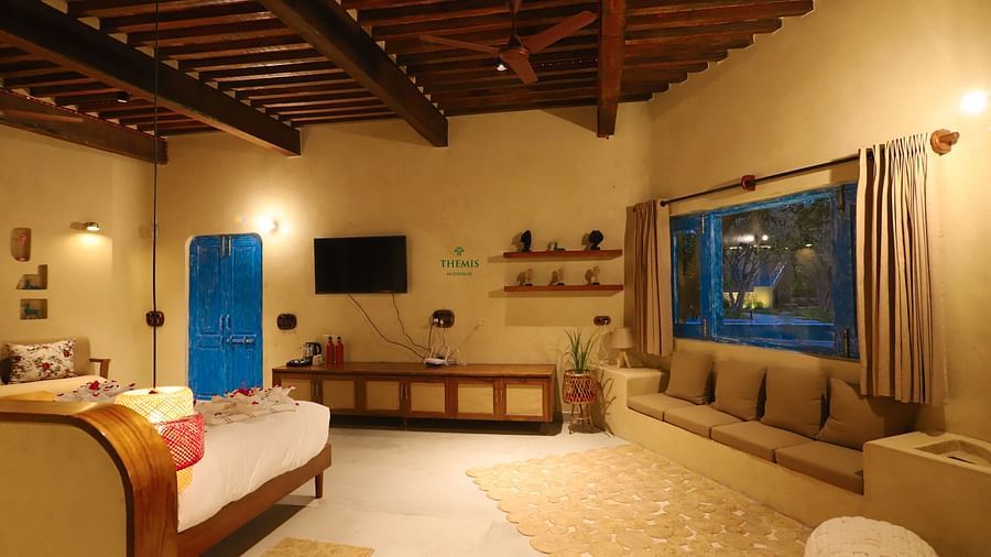 Classic King villa decked with a bed, couch and television at Themis Mudhouse - A Nature's Retreat Resort & Wellness