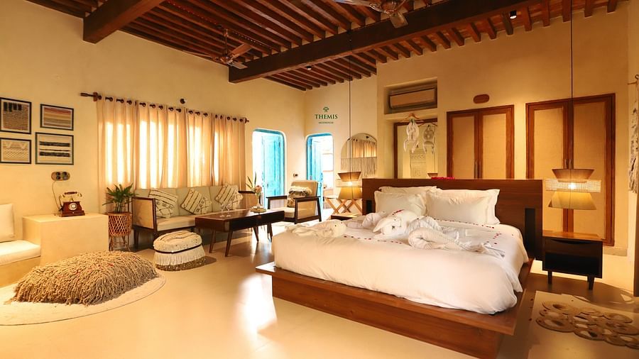 a villa decked with a bed and a couch overlooking a large window at Themis Mudhouse - A Nature's Retreat Resort & Wellness