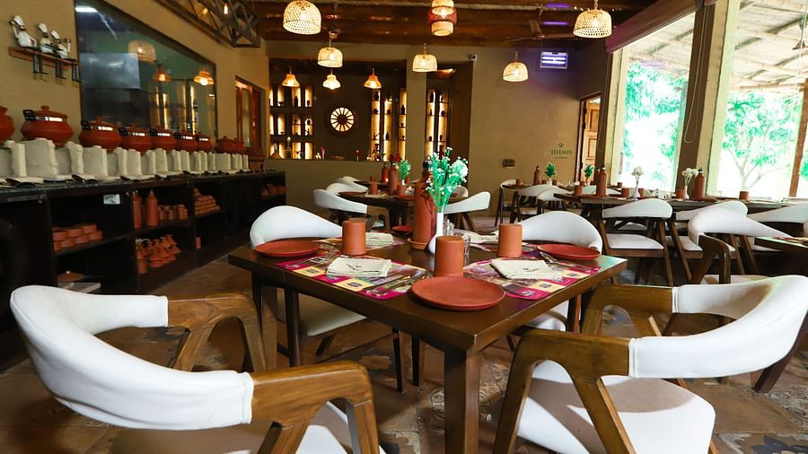 a view of a restaurant with table and plush chairs at Themis Mudhouse - A Nature's Retreat Resort & Wellness