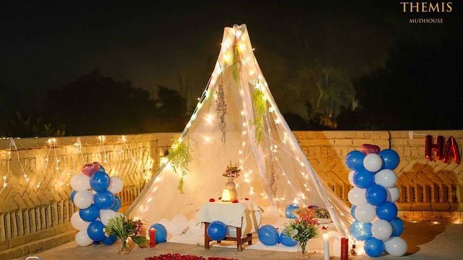 An image of a tent decorated with fairy lights and balloons at Themis Mudhouse - A Nature's Retreat Resort & Wellness