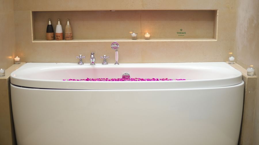 bathtub in luxurious suite decked with lotions and candles at Themis Mudhouse - A Nature's Retreat Resort & Wellness