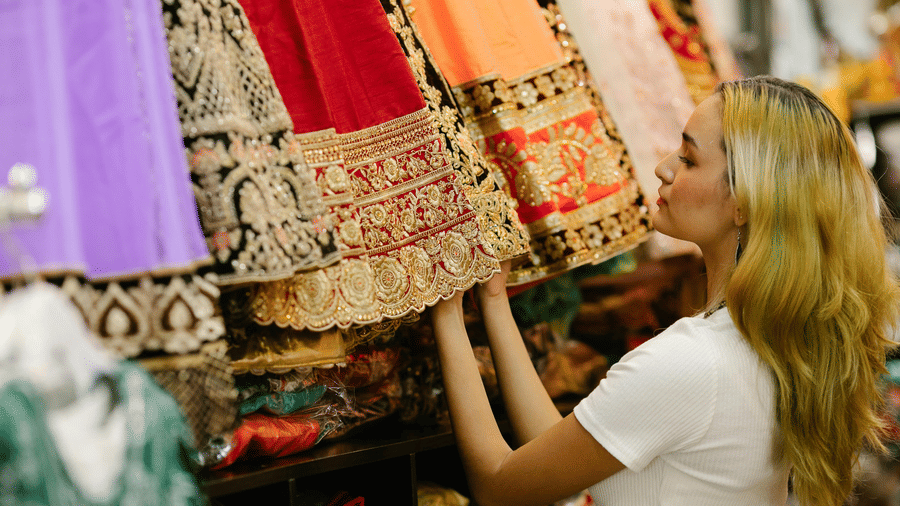 A women looking at heavy bridal attire inside a shop.