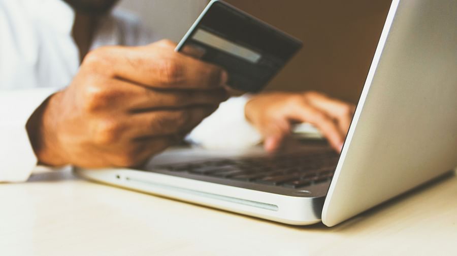 a person holding a credit card while using a laptop to make a payment for an online transaction