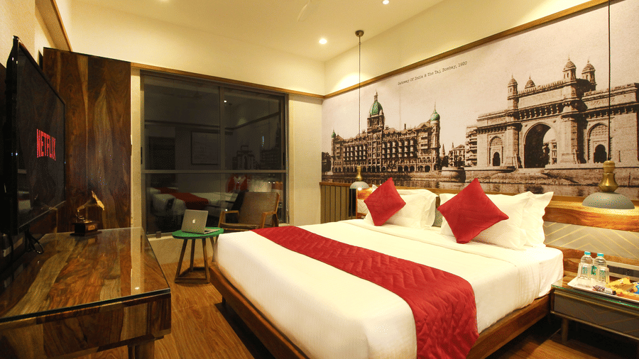 An overview of the 2 Bedroom Suite with a double bed, side tables, a tv, an expansive window overlooking the city in Khar area.