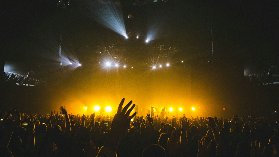 Packed crowd immersed in a live music show featuring vibrant stage lighting, visual effects, and a high-energy atmosphere
