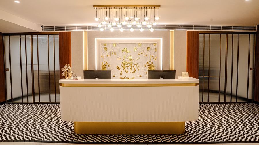 A vibrant reception desk featuring glowing ceiling lights, and monitors beside a designer wall at Triptam Hotel, Vrindavan