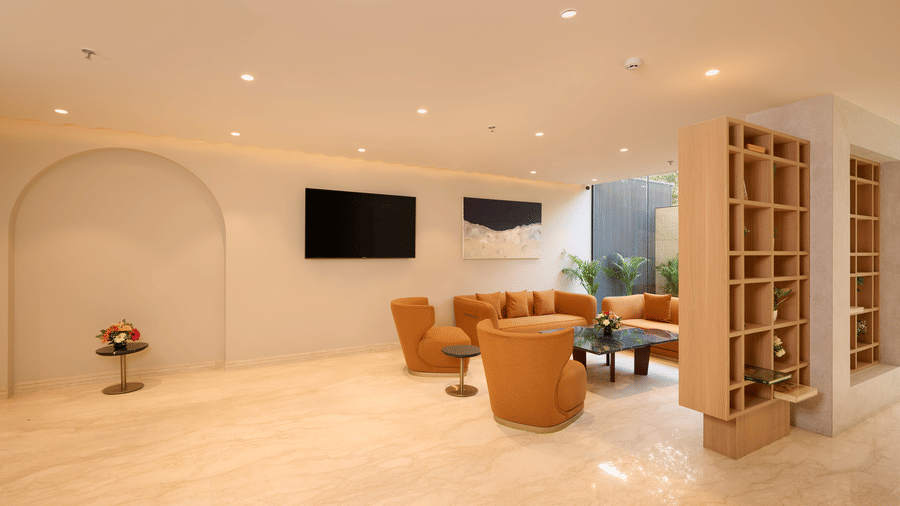 Interior lobby of Tulip Inn Gurugram with tan leather seating, marble floors, a wall-mounted TV, and a wooden room divider.