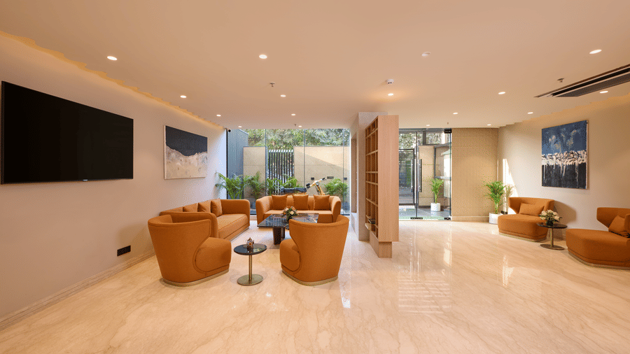 Wide-angle view of the Tulip Inn Gurugram lobby lounge, displaying marble flooring, leather seating areas, and large windows.