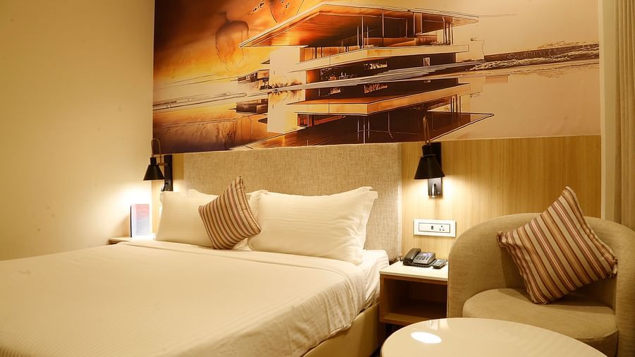 A close up shot of a bed placed beside a cosy chair and a teapoy in our hotel room in Zirakpur - Tulip Inn, Zirakpur