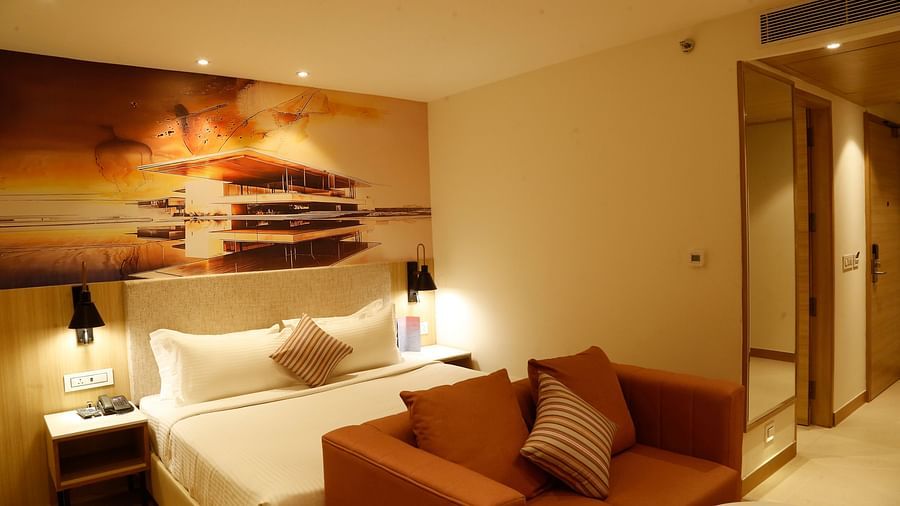 An image of our suite with an orange couch placed in front of a large king size bed - Tulip Inn, Zirakpur