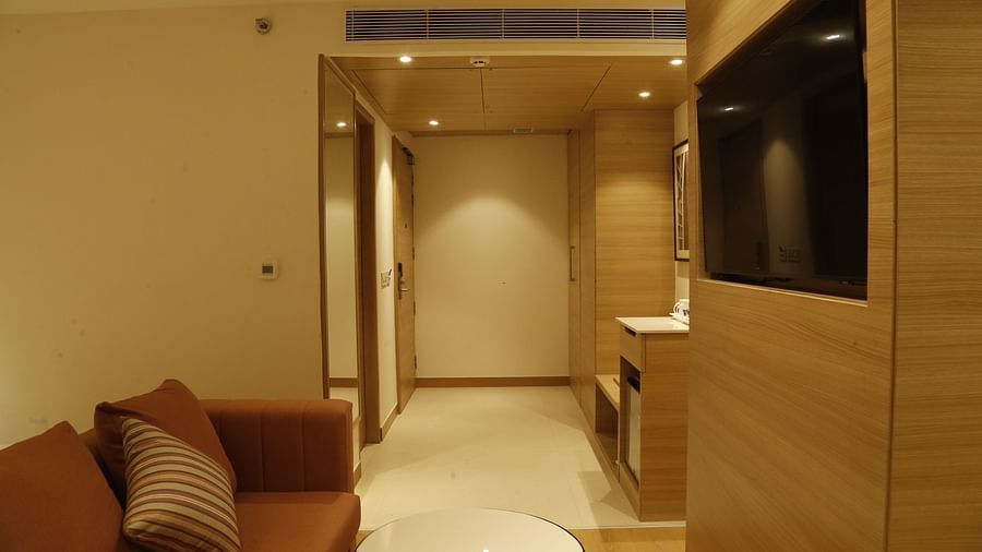 A seating area in our suite with an orange couch placed in front of a wall-mounted television - Tulip Inn, Zirakpur