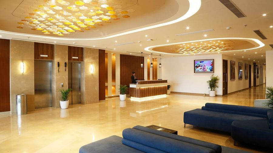 An image of a hotel lobby with blue couches, chandeliers and a reception desk - Tulip Inn, Zirakpur
