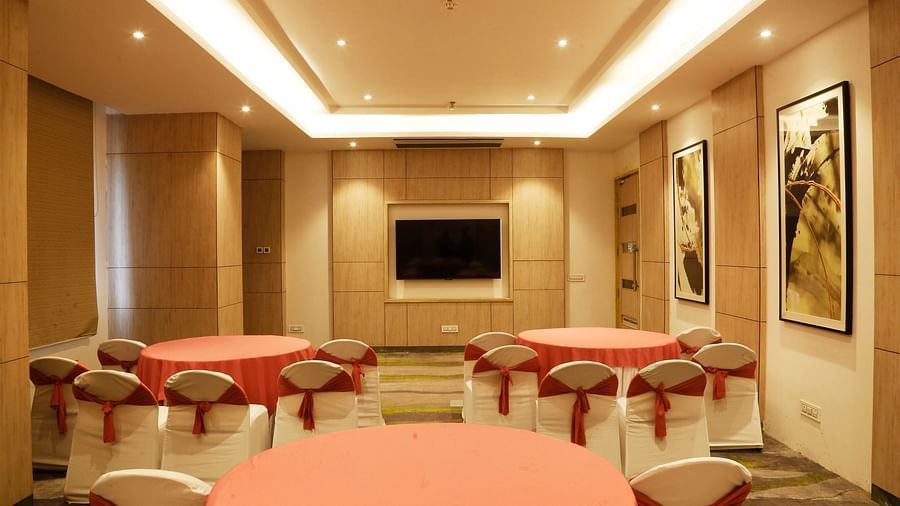 A conference hall in Zirakpur with the chairs turned towards a wall with a mounted television - Tulip Inn, Zirakpur