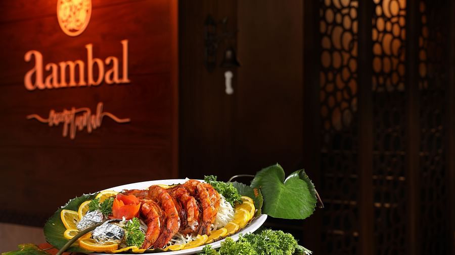 A platter of seafood placed on the table with the name of Aambal Restaurant highlighted on the wall in the background at Uday Backwater Resort
